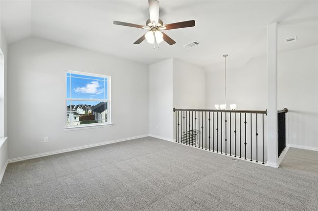 Empty room with vaulted ceiling, a ceiling fan, carpet floors, and a chandelier | Image 24