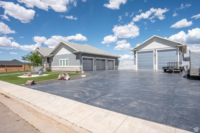 Ranch-style house with stone siding, a garage, a front lawn, and driveway | Image 103