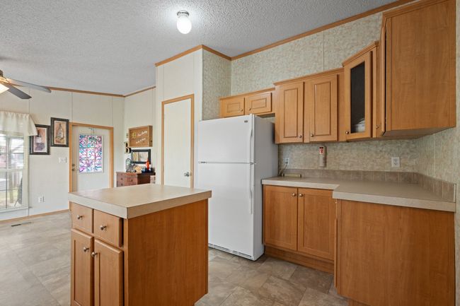 Kitchen featuring freestanding refrigerator, ceiling fan, ornamental molding, a textured ceiling, and light countertops | Image 11