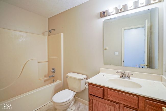 full bath featuring vanity, tub / shower combination, a textured ceiling, and tile patterned floors | Image 30