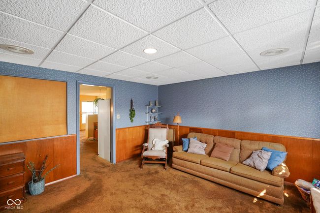 carpeted living room featuring a drop ceiling, a wainscoted wall, and wood walls | Image 27