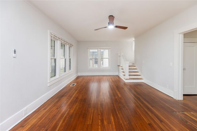 Spare room with stairs, a ceiling fan, crown molding, baseboards, and wood-type flooring | Image 34