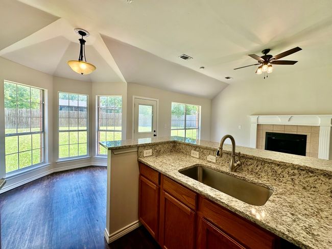 Kitchen with vaulted ceiling, open floor plan, dark wood-style flooring, pendant lighting, and light stone counters | Image 6