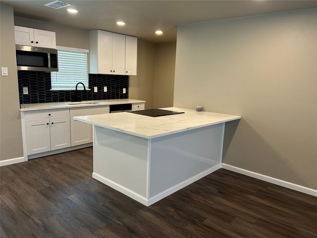 Kitchen featuring stainless steel microwave, a sink, dark wood-style floors, baseboards, and recessed lighting | Image 23