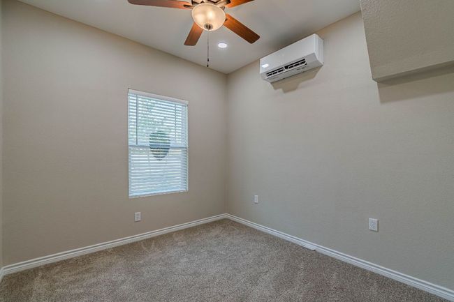 Carpeted empty room with a wall mounted air conditioner, ceiling fan, and recessed lighting | Image 23