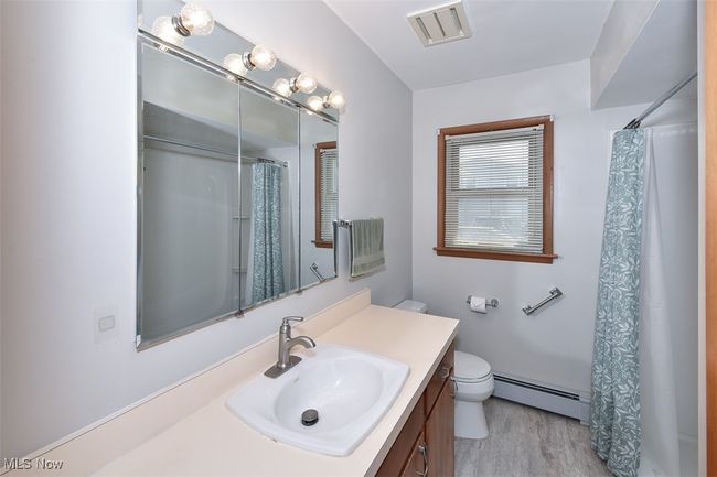 Full bath featuring visible vents, toilet, vanity, a shower with curtain, and baseboard heating | Image 37