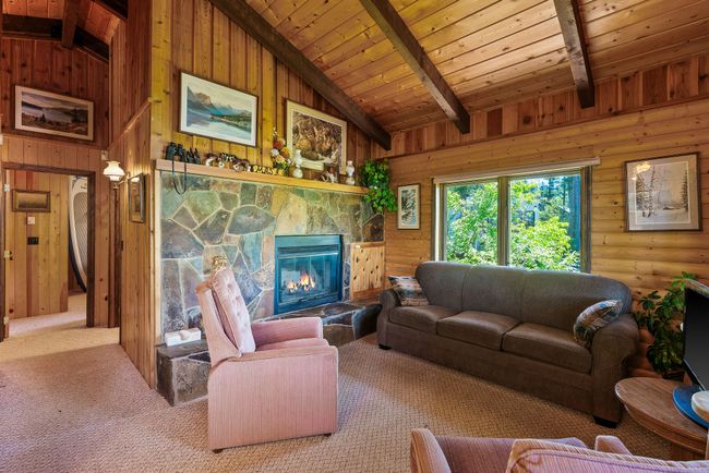 Living area with wooden ceiling, a fireplace, wood walls, and carpet floors | Image 14