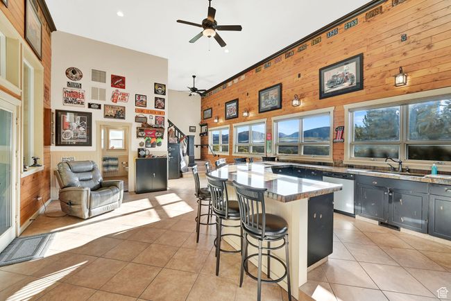 Kitchen featuring a kitchen breakfast bar, high vaulted ceiling, dishwasher, light tile patterned floors, and ceiling fan | Image 38