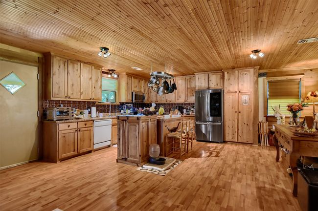 Kitchen with visible vents, light wood finished floors, a kitchen bar, tasteful backsplash, and appliances with stainless steel finishes | Image 18