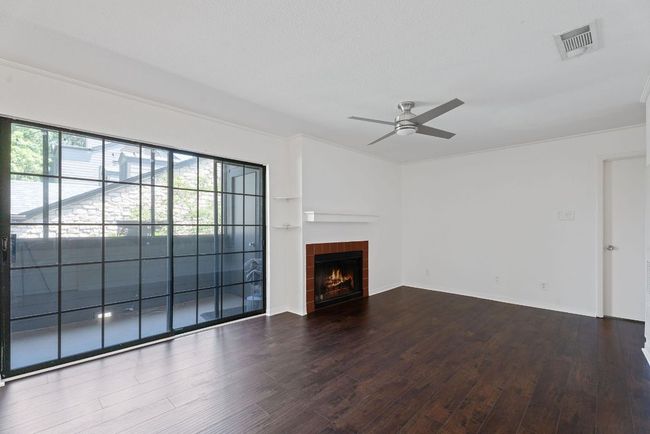 The spacious living room boasts a cozy wood-burning fireplace and large glass sliders that open onto your screened-in balcony. | Image 11