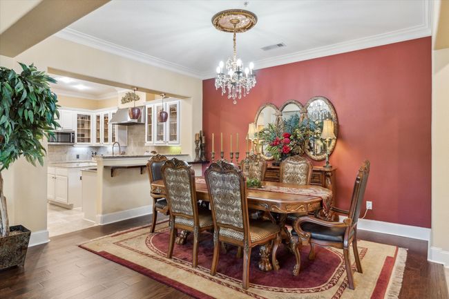 Dining area featuring a chandelier, wood finished floors, ornamental molding, and baseboards | Image 5