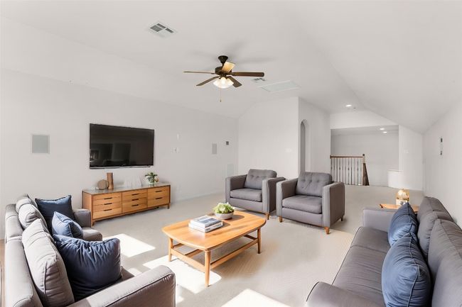 Carpeted living room with vaulted ceiling, visible vents, arched walkways, and ceiling fan | Image 36