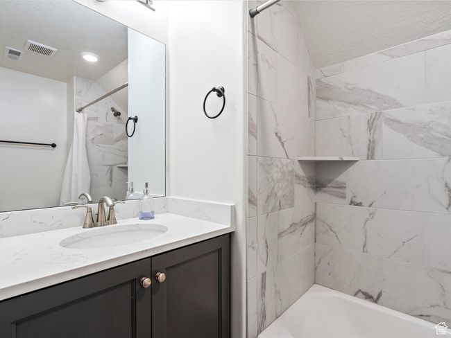 Bathroom with a textured ceiling, vanity, and shower / tub combo | Image 26