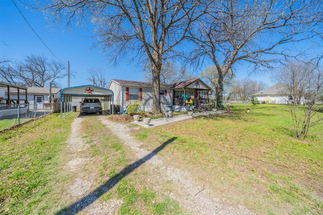 View of front of house with a detached carport, a front lawn, fence, and driveway | Image 16