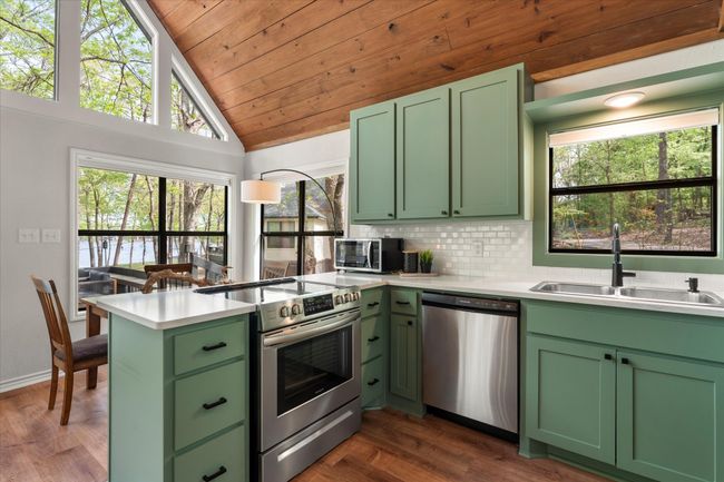 Kitchen with stainless steel appliances, vaulted ceiling, wooden ceiling, a sink, and green cabinets | Image 24