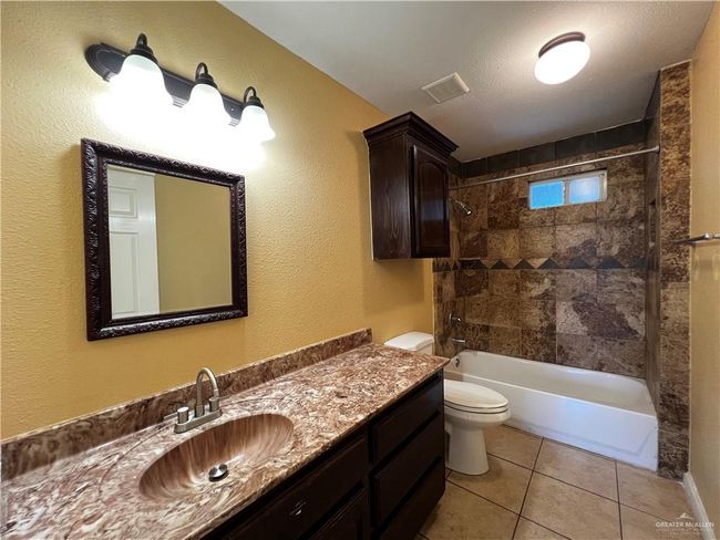 Bathroom with toilet, vanity, tile patterned flooring, and shower / tub combination | Image 10
