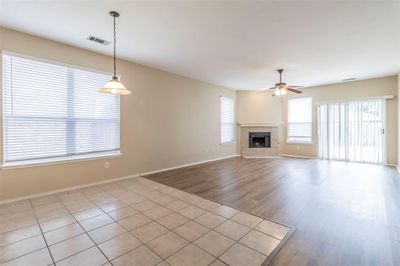 Unfurnished living room featuring ceiling fan, light wood-type flooring, and a tile fireplace | Image 2