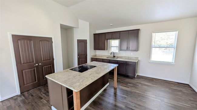 Kitchen with black electric stovetop, dark brown cabinetry, a kitchen island, a sink, and plenty of natural light | Image 13