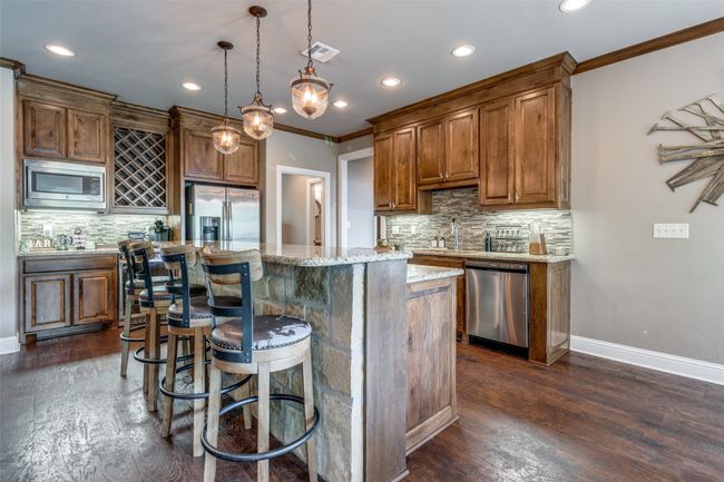 Kitchen featuring ornamental molding, dark wood-type flooring, a kitchen island, appliances with stainless steel finishes, and backsplash | Image 6