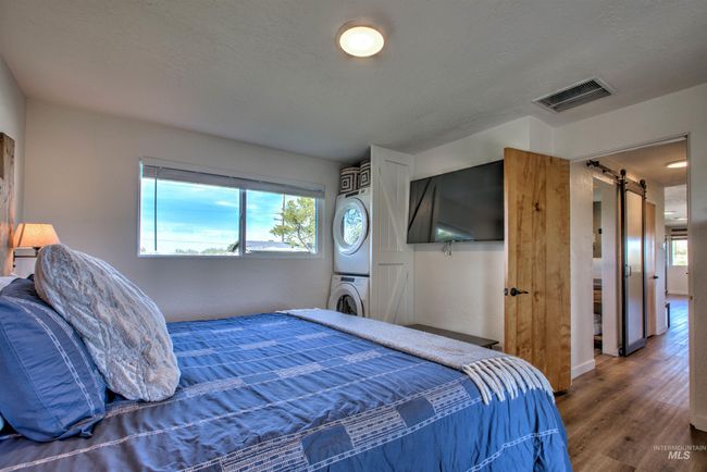 Bedroom with stacked washer / dryer, multiple windows, wood finished floors, and a barn door | Image 18