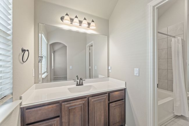 Full bathroom featuring vanity, shower / tub combo, tile patterned flooring, and lofted ceiling | Image 30
