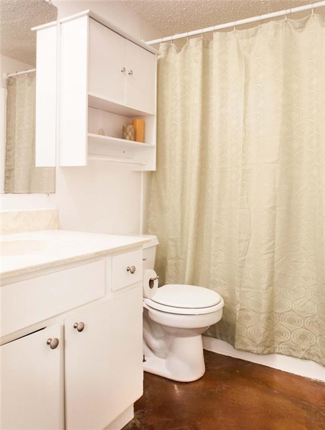 Full bath featuring a textured ceiling, vanity, concrete flooring, and a shower with shower curtain | Image 4