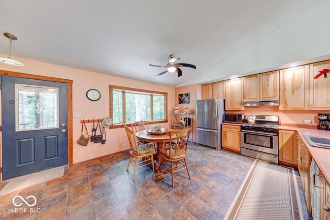 kitchen featuring appliances with stainless steel finishes, under cabinet range hood, light brown cabinetry, vaulted ceiling, and light countertops | Image 43