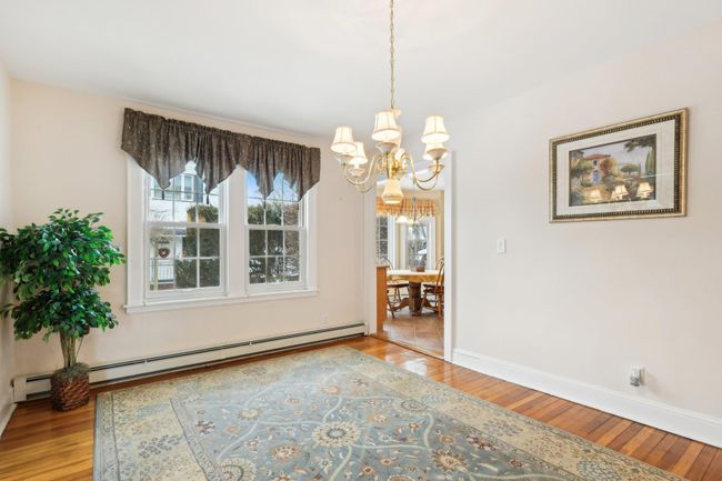 Unfurnished dining area with a baseboard radiator, a notable chandelier, and light hardwood / wood-style floors | Image 11