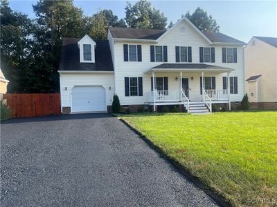 Colonial-style house with covered porch and a front yard | Image 1