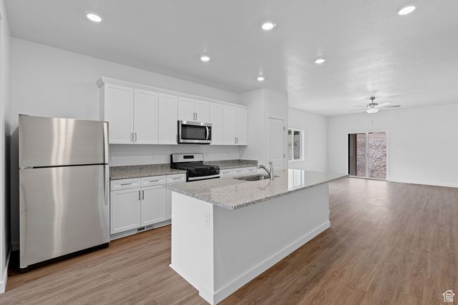Kitchen featuring white cabinets, light wood-style flooring, a sink, and appliances with stainless steel finishes | Image 4
