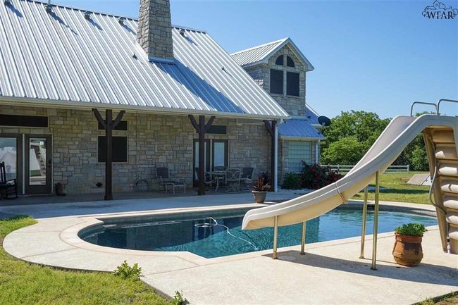 View of swimming pool with a patio area and a water slide | Image 9