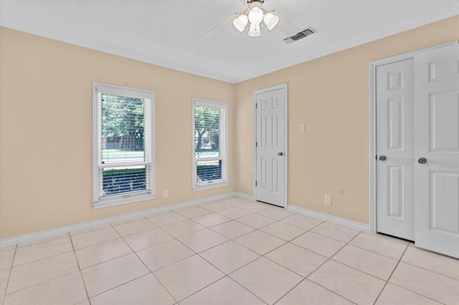 Unfurnished bedroom featuring light tile patterned flooring, crown molding, and ceiling fan | Image 19