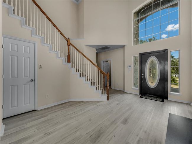 Foyer with stairway, wood finished floors, and a towering ceiling | Image 13