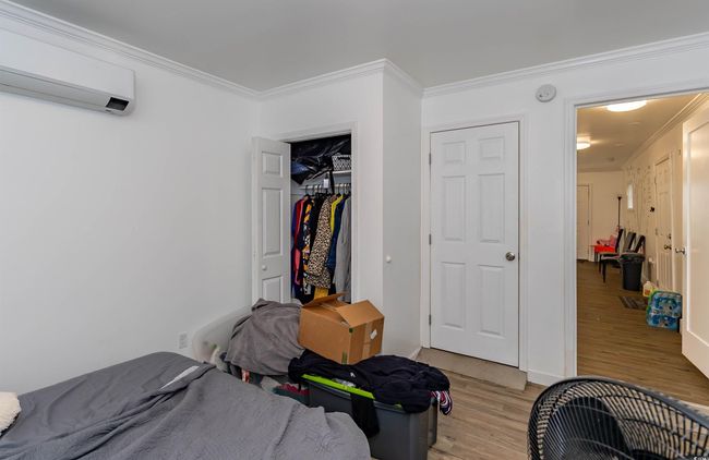 Bedroom with crown molding, light wood finished floors, a wall mounted AC, and a closet | Image 22