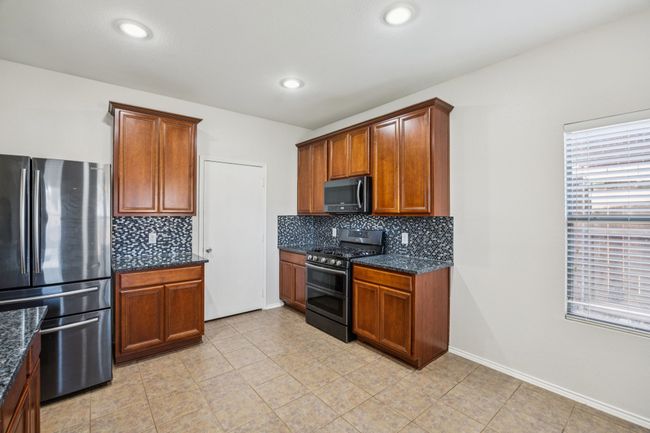 Kitchen featuring appliances with stainless steel finishes, decorative backsplash, dark stone countertops, recessed lighting, and brown cabinetry | Image 11