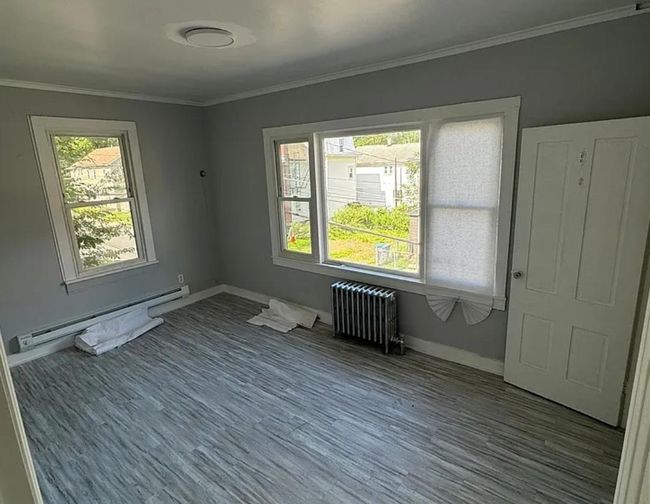 Spare room with baseboard heating, wood finished floors, baseboards, radiator, and ornamental molding | Image 5