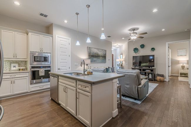 Kitchen with stainless steel appliances, a sink, open floor plan, a ceiling fan, and dark wood-style flooring | Image 14