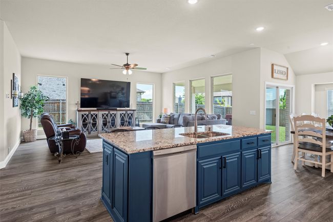 Kitchen with stainless steel dishwasher, blue cabinetry, open floor plan, an island with sink, and recessed lighting | Image 10