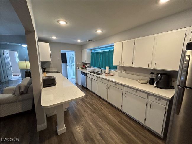 Kitchen featuring appliances with stainless steel finishes, white cabinetry, light countertops, dark wood-type flooring, and recessed lighting | Image 5