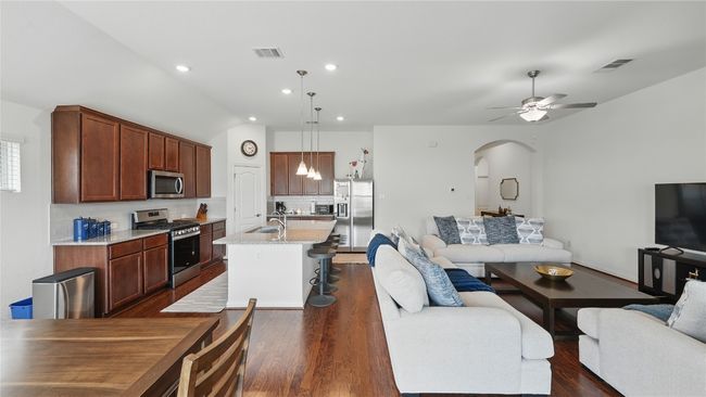 Living room featuring arched walkways, dark wood finished floors, a ceiling fan, and recessed lighting | Image 6