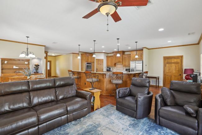 Living area with crown molding, wood finished floors, visible vents, ceiling fan, and recessed lighting | Image 8