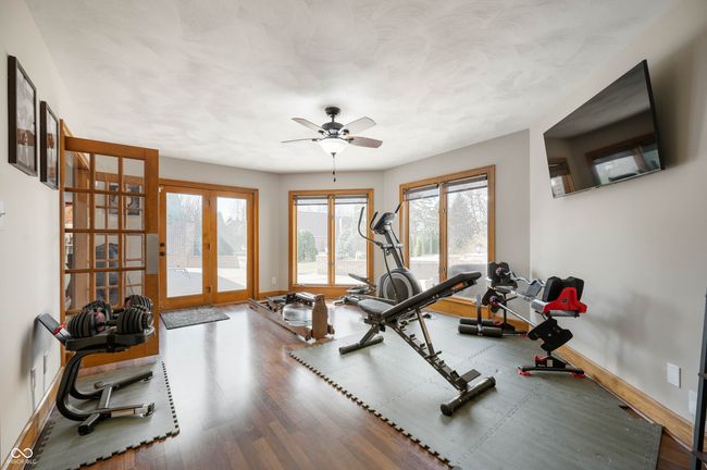 exercise room with a ceiling fan, wood finished floors, baseboards, and french doors | Image 20