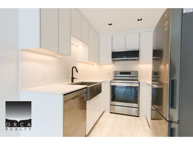 Kitchen with stainless steel appliances, extractor fan, white cabinets, light countertops, and modern cabinets | Image 13