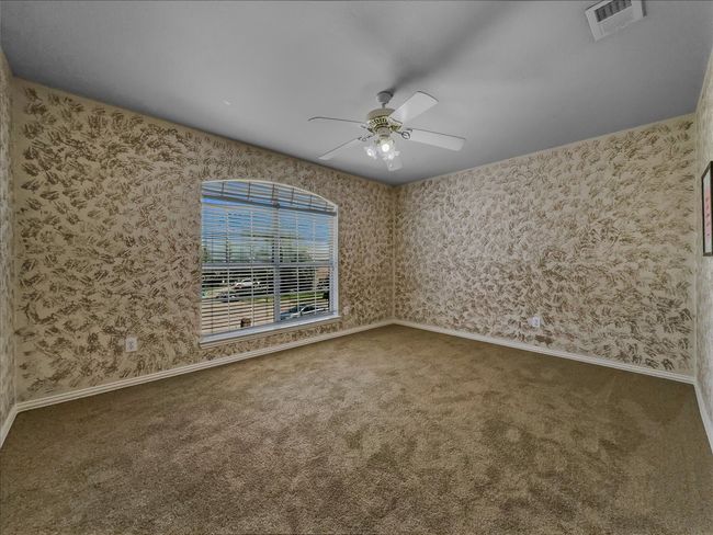 Empty room with wallpapered walls, carpet flooring, and ceiling fan | Image 22