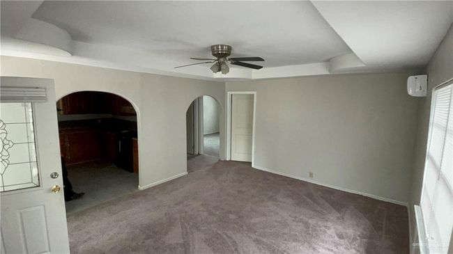 Unfurnished room with a ceiling fan, a tray ceiling, carpet flooring, and arched walkways | Image 7