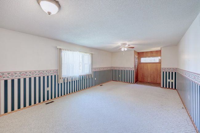 Carpeted spare room with ceiling fan, a textured ceiling, and a wainscoted wall | Image 16