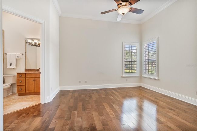 This bright and spacious ensuite bedroom features rich hardwood floors, plantation shutters, and a private bath—ideal for guests or multi-generational living. | Image 17