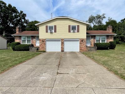 Split level home featuring cooling unit, a garage, and a front yard | Image 1