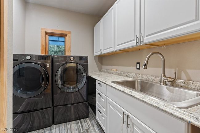 Laundry area featuring washer and clothes dryer, a sink, and cabinet space | Image 60