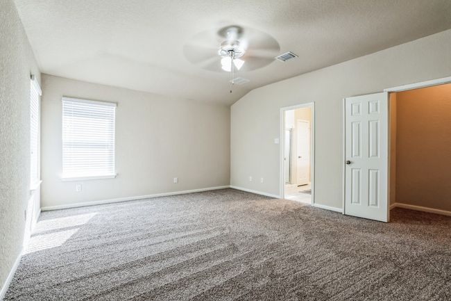 Unfurnished bedroom featuring ensuite bathroom, vaulted ceiling, a textured ceiling, ceiling fan, and light colored carpet | Image 11